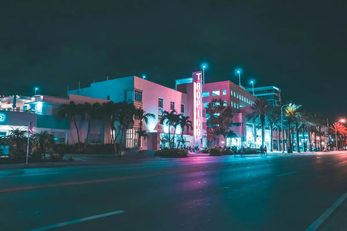 Neon hotel signs along a Miami Beach street at night